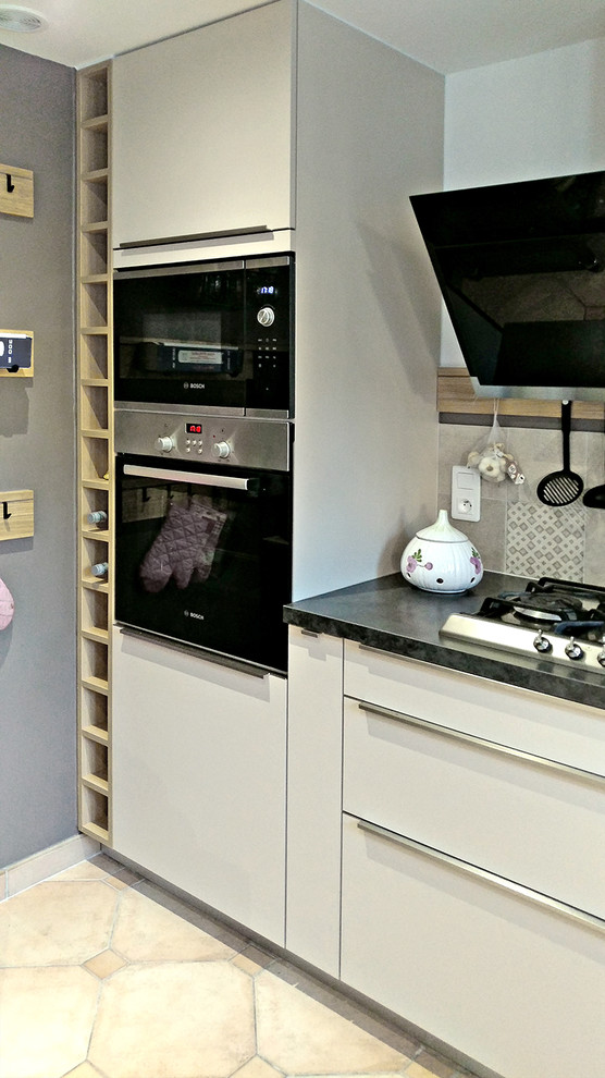 Photo of a large urban l-shaped kitchen/diner in Other with a single-bowl sink, beaded cabinets, beige cabinets, laminate countertops, multi-coloured splashback, cement tile splashback, black appliances, ceramic flooring, an island, beige floors and grey worktops.