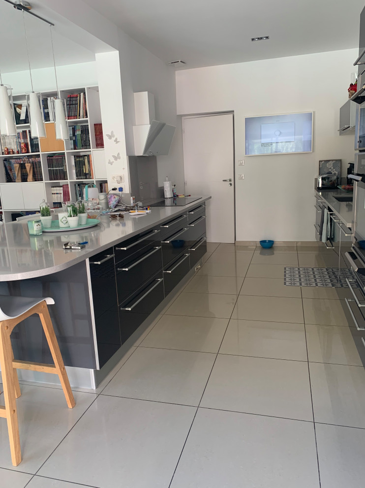 Foto på ett funkis grå linjärt kök och matrum, med grå skåp, granitbänkskiva, en köksö och beiget golv