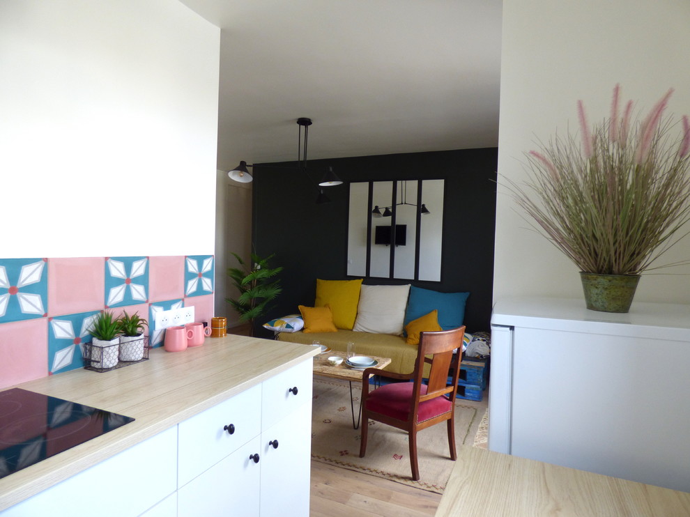 Пример оригинального дизайна: параллельная кухня-гостиная среднего размера в стиле фьюжн с одинарной мойкой, плоскими фасадами, белыми фасадами, деревянной столешницей, розовым фартуком, фартуком из цементной плитки, черной техникой, полом из керамической плитки, зеленым полом и коричневой столешницей