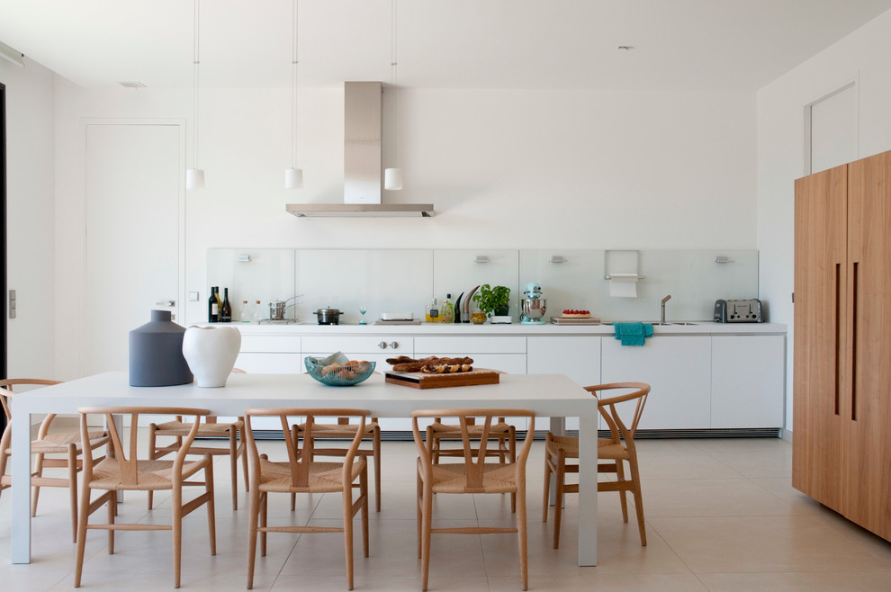 Bild på ett stort funkis linjärt kök och matrum, med släta luckor, vita skåp, glaspanel som stänkskydd och integrerade vitvaror