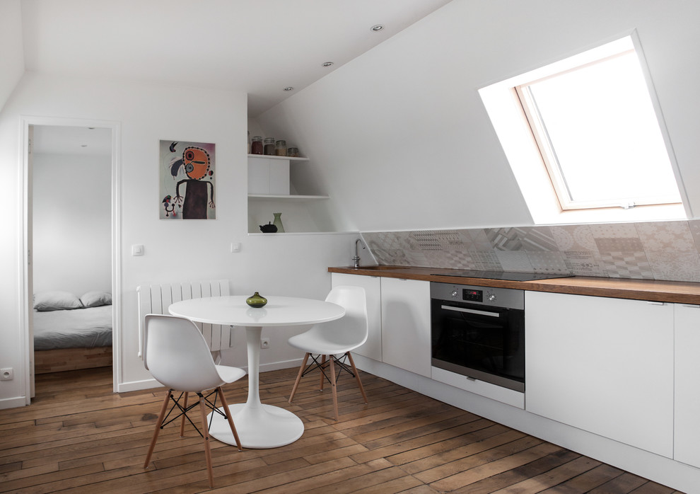 Foto di una piccola cucina design con lavello sottopiano, ante bianche, top in legno, paraspruzzi grigio, elettrodomestici in acciaio inossidabile e pavimento in legno massello medio