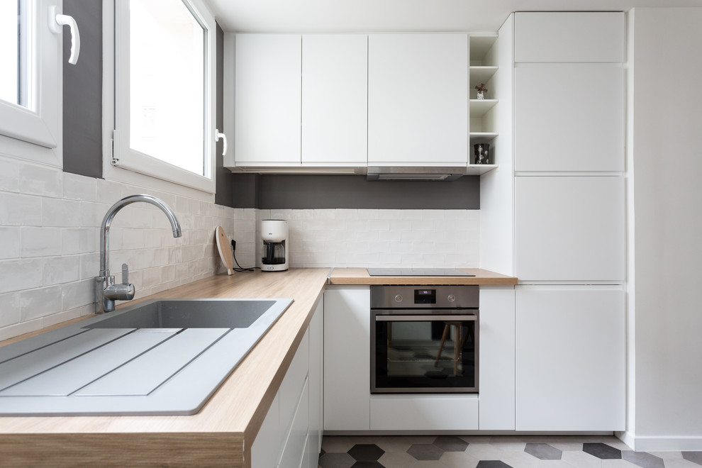 Design ideas for a medium sized modern u-shaped kitchen/diner in Other with a single-bowl sink, beaded cabinets, white cabinets, wood worktops, white splashback, terracotta splashback, stainless steel appliances, cement flooring, no island, grey floors and beige worktops.