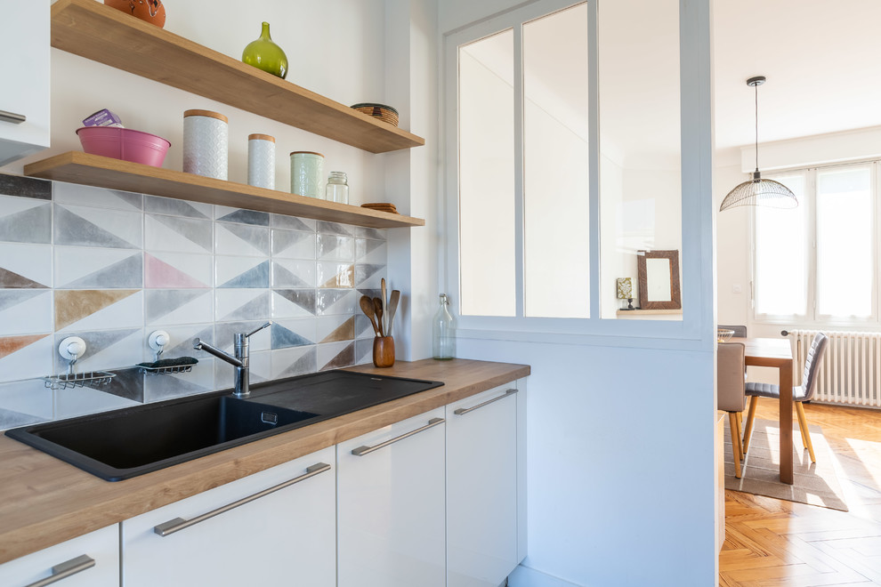 Immagine di una cucina scandinava chiusa con lavello da incasso, ante lisce, ante bianche, top in legno e top marrone