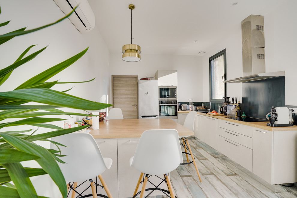 Bild på ett stort funkis linjärt kök med öppen planlösning, med vita skåp, träbänkskiva, grått stänkskydd, målat trägolv, en köksö och grått golv