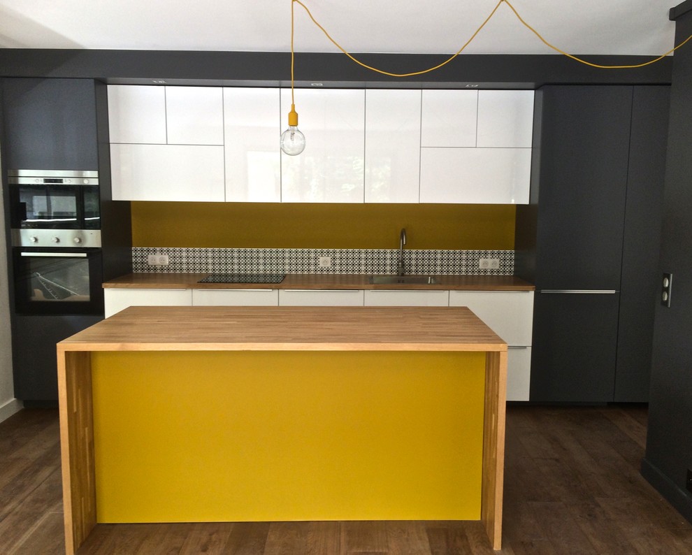 Trendy galley light wood floor eat-in kitchen photo in Paris with an undermount sink, white cabinets, wood countertops, yellow backsplash, ceramic backsplash, paneled appliances and an island
