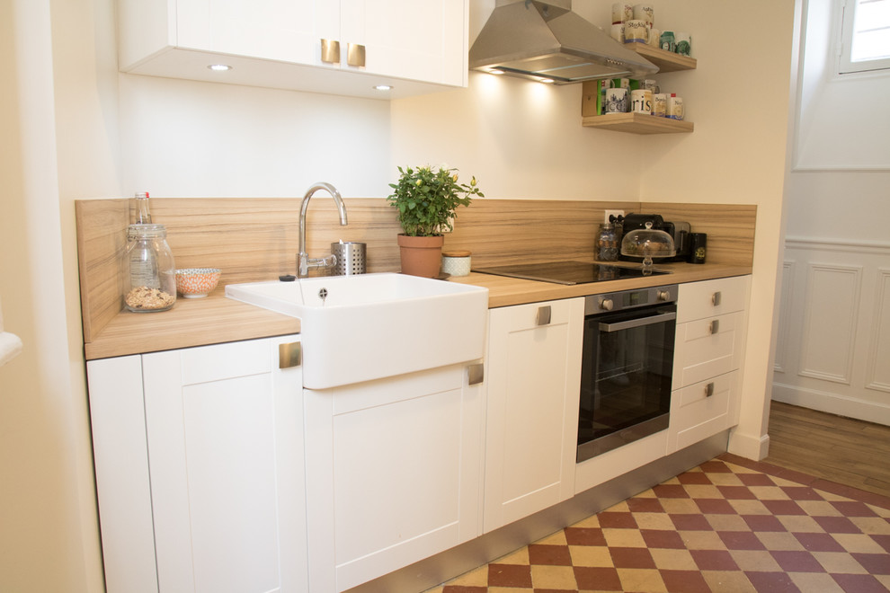 Cette image montre une cuisine ouverte linéaire et encastrable vintage avec un placard à porte affleurante, des portes de placard blanches et un plan de travail en bois.