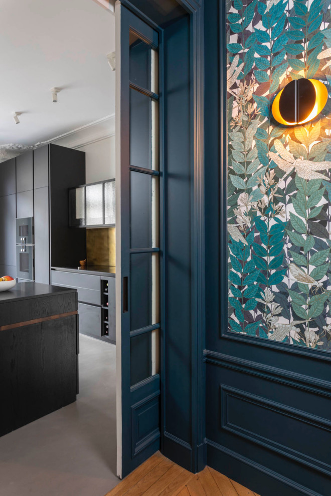 Large contemporary single-wall enclosed kitchen in Paris with a submerged sink, black cabinets, granite worktops, metallic splashback, integrated appliances, concrete flooring, an island, grey floors and black worktops.