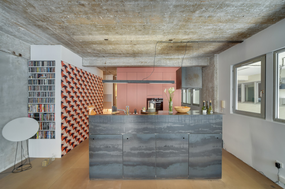 Cette image montre une cuisine ouverte urbaine avec un placard à porte plane, des portes de placard oranges, un électroménager en acier inoxydable, îlot, un sol gris et un plan de travail gris.