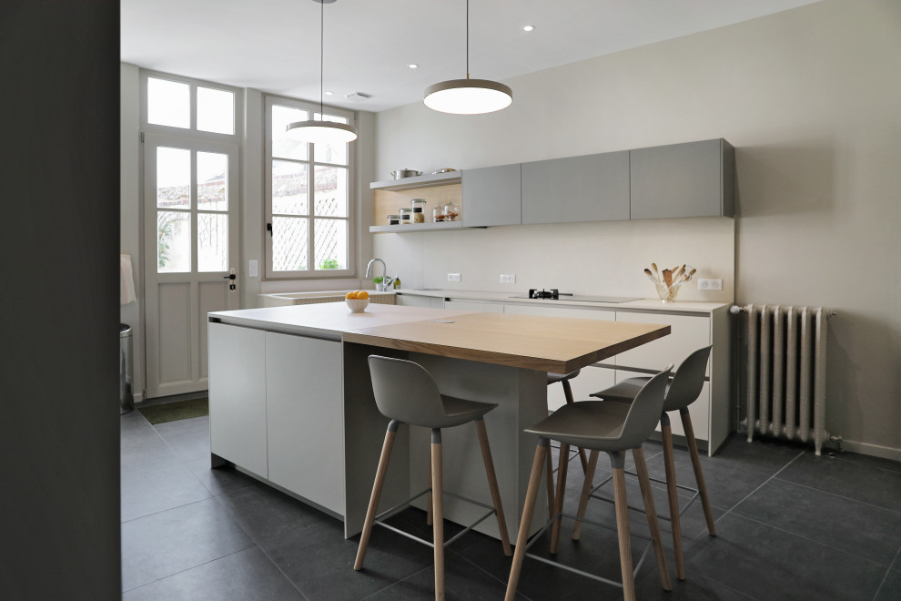 Immagine di una cucina design di medie dimensioni con lavello integrato, ante lisce, ante grigie, paraspruzzi beige, elettrodomestici da incasso, pavimento in gres porcellanato, pavimento nero e top beige