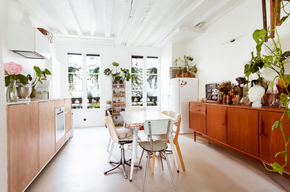 Photo of a medium sized bohemian single-wall kitchen/diner in Paris with a submerged sink, beaded cabinets, light wood cabinets, quartz worktops, white splashback, white appliances, concrete flooring, a breakfast bar, grey floors and white worktops.