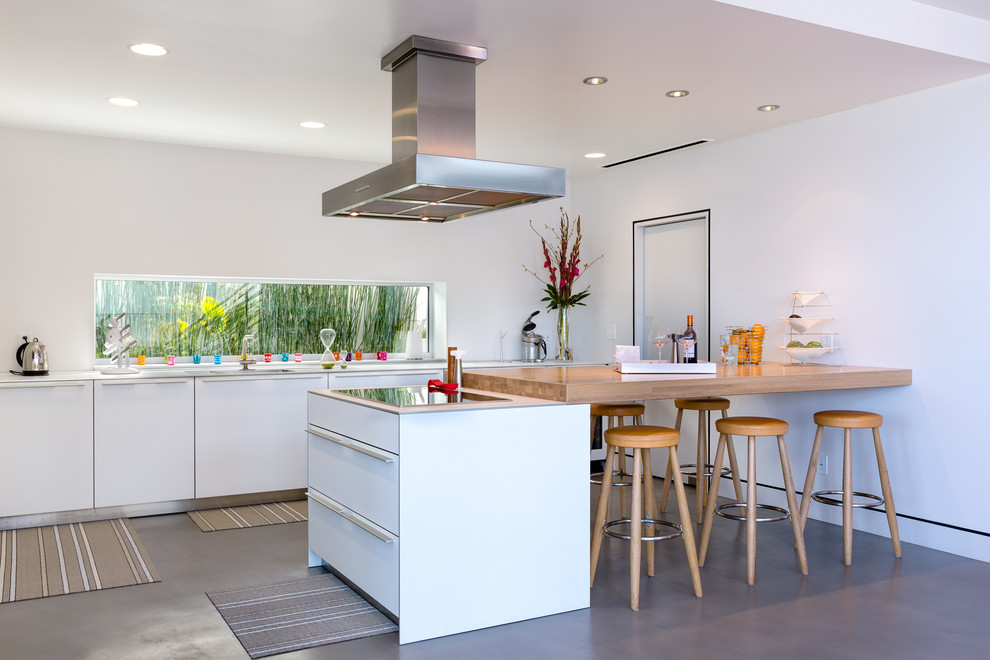 Moderne Küche mit Betonboden, flächenbündigen Schrankfronten, weißen Schränken und Kücheninsel in Orange County