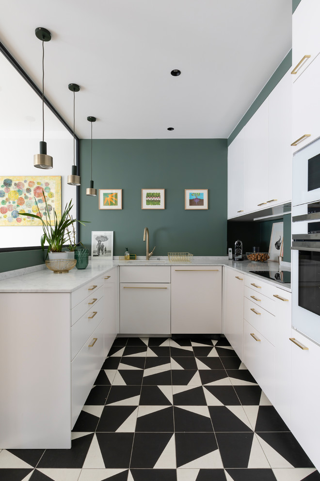 Стильный дизайн: п-образная кухня среднего размера в современном стиле с белыми фасадами, зеленым фартуком, белой техникой, полом из керамогранита, белой столешницей, врезной мойкой, плоскими фасадами и разноцветным полом - последний тренд