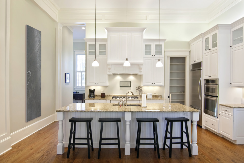 Inspiration for a timeless l-shaped medium tone wood floor and brown floor kitchen remodel in Paris with raised-panel cabinets, white cabinets, white backsplash, stainless steel appliances and an island