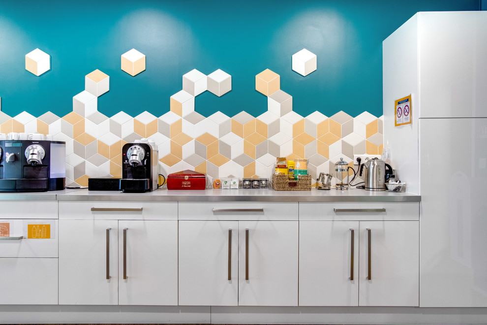Inspiration för ett stort minimalistiskt grå linjärt grått kök med öppen planlösning, med en dubbel diskho, luckor med profilerade fronter, vita skåp, laminatbänkskiva, gult stänkskydd, stänkskydd i keramik, vita vitvaror, vinylgolv, en köksö och brunt golv