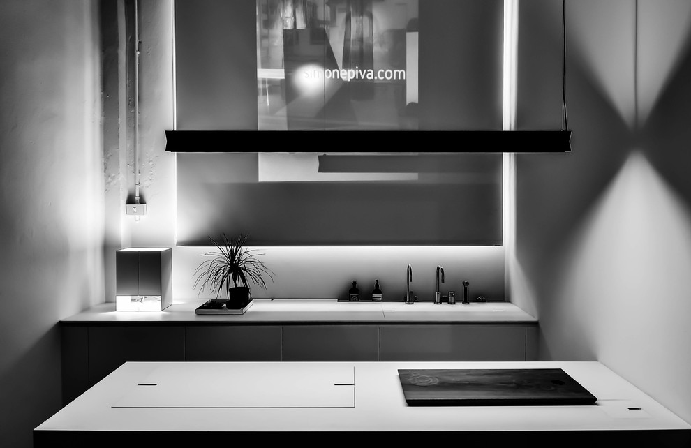 Inspiration pour une petite cuisine parallèle design avec un évier intégré, un plan de travail en surface solide, une crédence blanche, un électroménager en acier inoxydable et îlot.