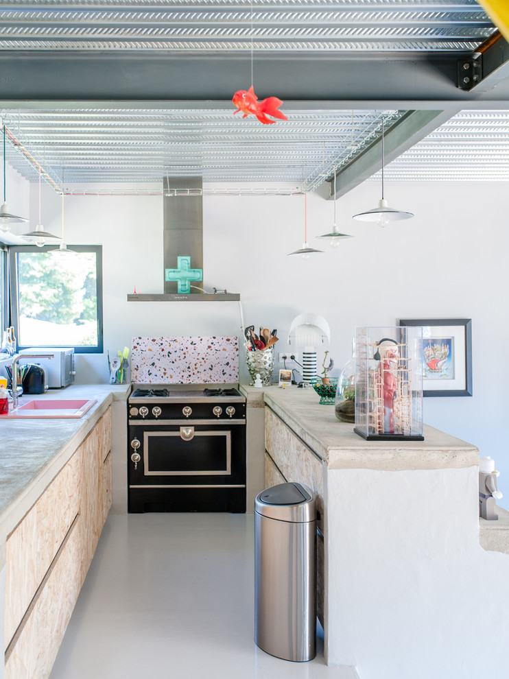 This is an example of an urban kitchen in Montpellier with a built-in sink, flat-panel cabinets, light wood cabinets, multi-coloured splashback, black appliances, a breakfast bar, white floors and beige worktops.
