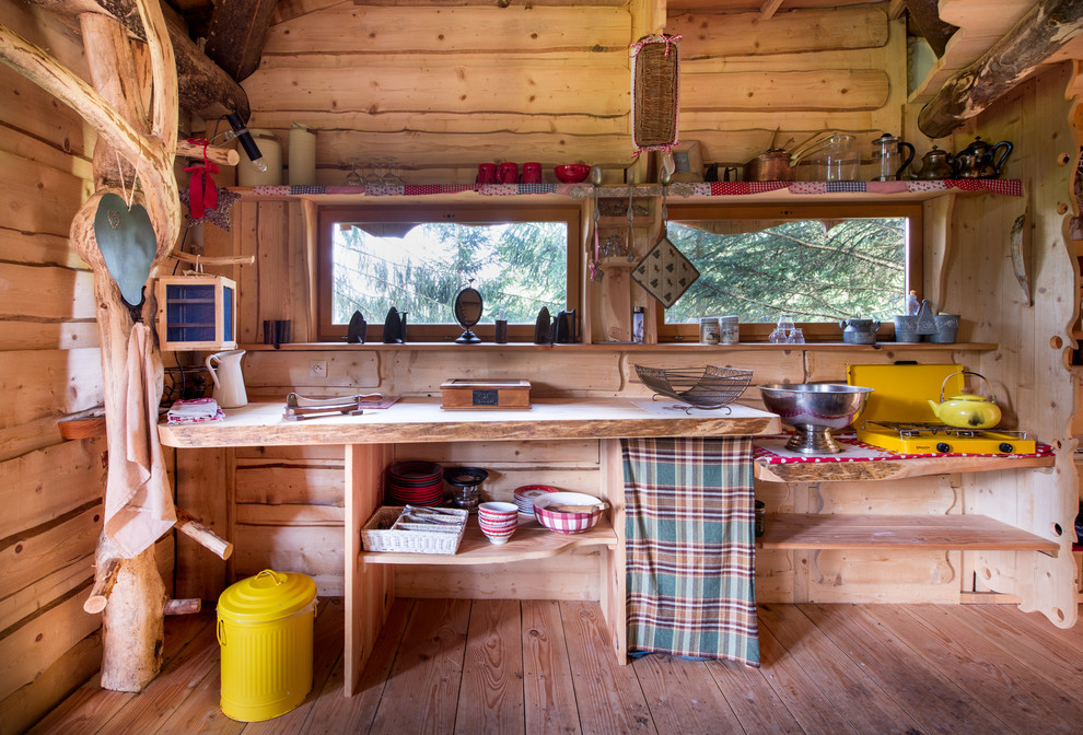 Cette photo montre une petite cuisine montagne en bois brun fermée avec un placard sans porte, un plan de travail en bois, un sol en bois brun, aucun îlot, une crédence marron et une crédence en bois.
