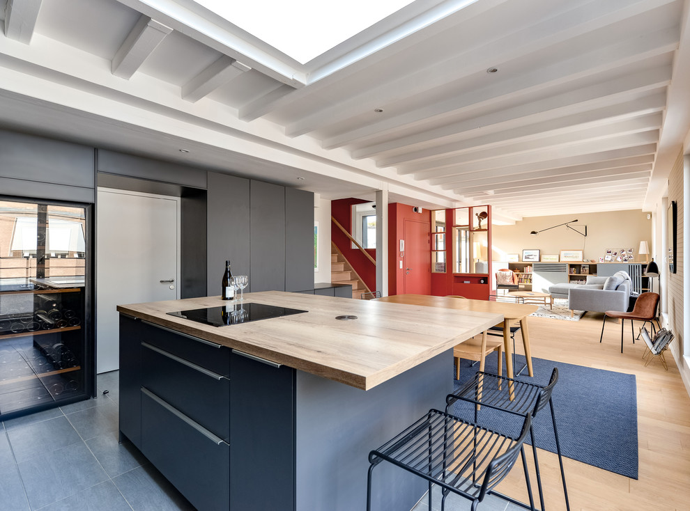 パリにある高級な広いコンテンポラリースタイルのおしゃれなキッチン (アンダーカウンターシンク、インセット扉のキャビネット、グレーのキャビネット、木材カウンター、ベージュキッチンパネル、木材のキッチンパネル、黒い調理設備、セラミックタイルの床、グレーの床、ベージュのキッチンカウンター) の写真