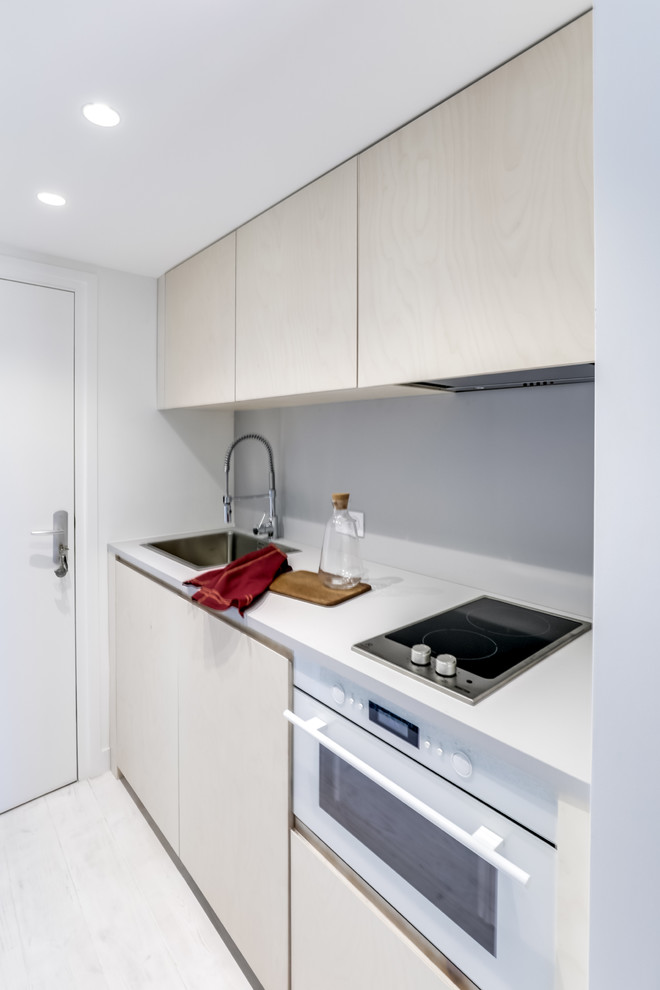 Foto på ett litet minimalistiskt linjärt kök med öppen planlösning, med en undermonterad diskho, luckor med profilerade fronter, skåp i ljust trä, bänkskiva i koppar, grått stänkskydd, vita vitvaror, målat trägolv och vitt golv