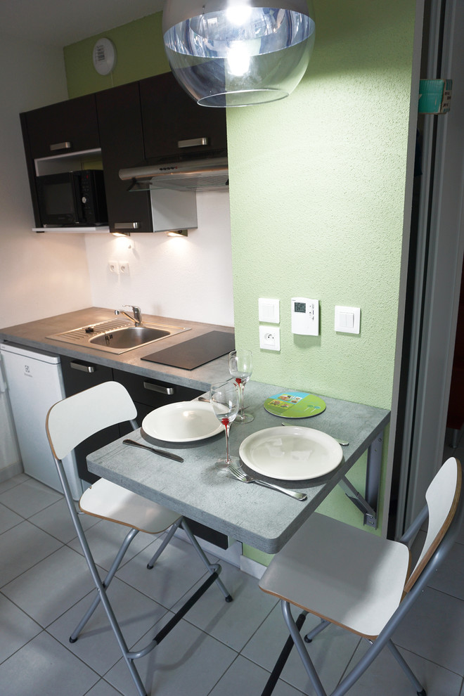 Kleine Moderne Wohnküche in L-Form mit Unterbauwaschbecken, grauen Schränken, Laminat-Arbeitsplatte, Küchenrückwand in Weiß, weißen Elektrogeräten, Keramikboden und Kücheninsel in Straßburg