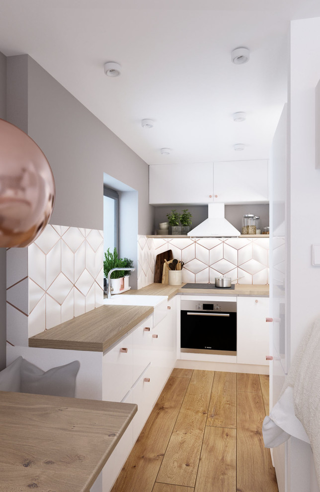 Photo of a small contemporary l-shaped open plan kitchen in Paris with flat-panel cabinets, white cabinets, wood worktops, white splashback, cement tile splashback, light hardwood flooring and no island.