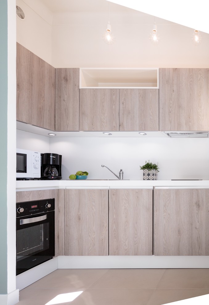Идея дизайна: прямая кухня-гостиная в современном стиле с одинарной мойкой, плоскими фасадами, светлыми деревянными фасадами, столешницей из ламината, белым фартуком, техникой под мебельный фасад и полом из керамической плитки без острова