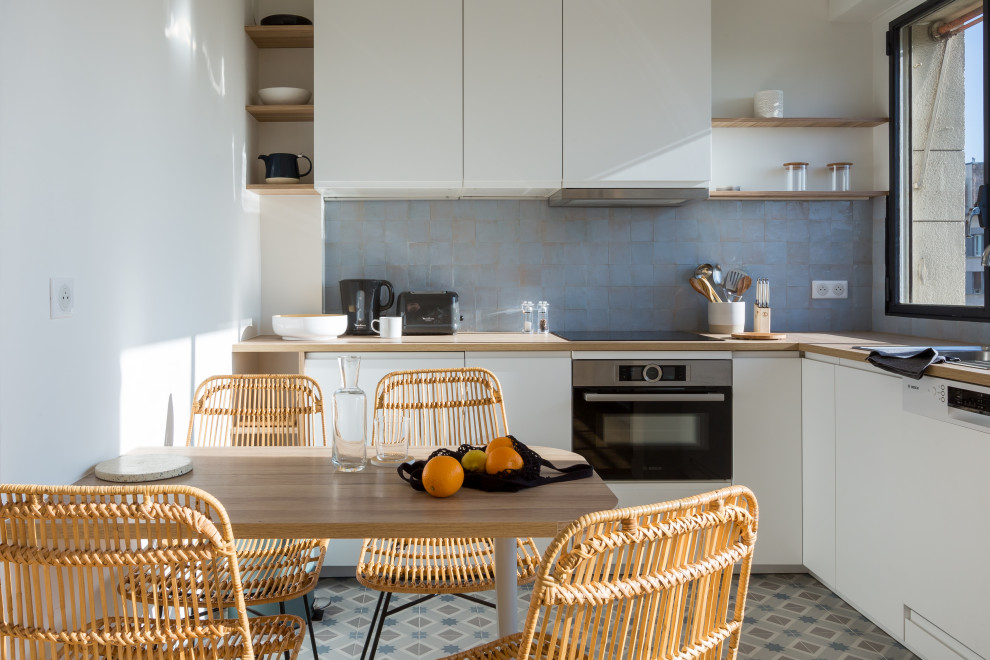 Immagine di una cucina a L design con ante lisce, ante bianche, top in legno, paraspruzzi blu, nessuna isola, pavimento multicolore e top beige