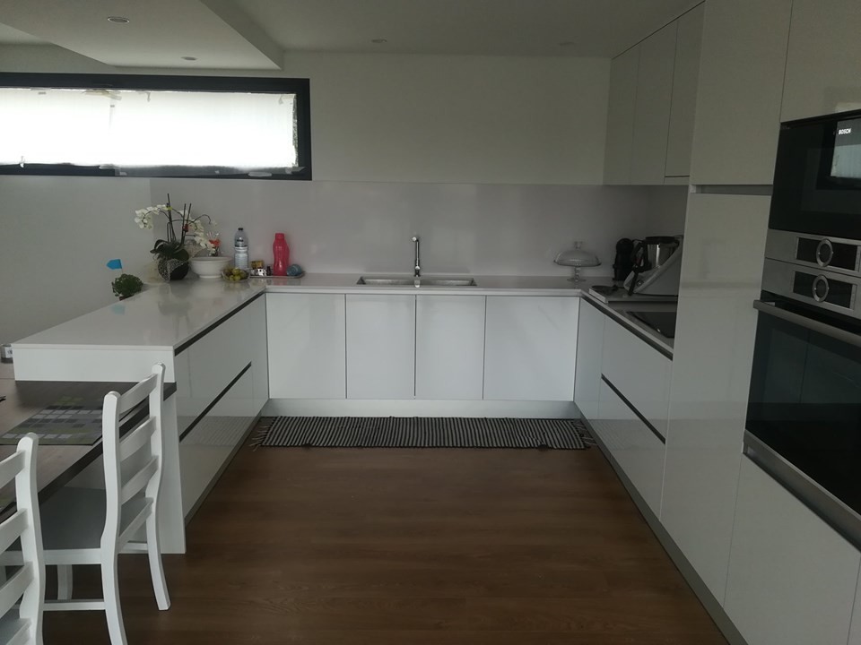 Cette photo montre une cuisine moderne en U avec un plan de travail en quartz, une crédence blanche, îlot et un plan de travail blanc.