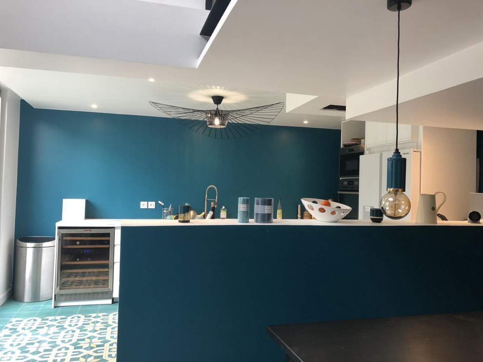 Large contemporary u-shaped open plan kitchen in Paris with a single-bowl sink, beaded cabinets, white cabinets, wood worktops, blue splashback, stainless steel appliances, cement flooring, an island, multi-coloured floors and white worktops.