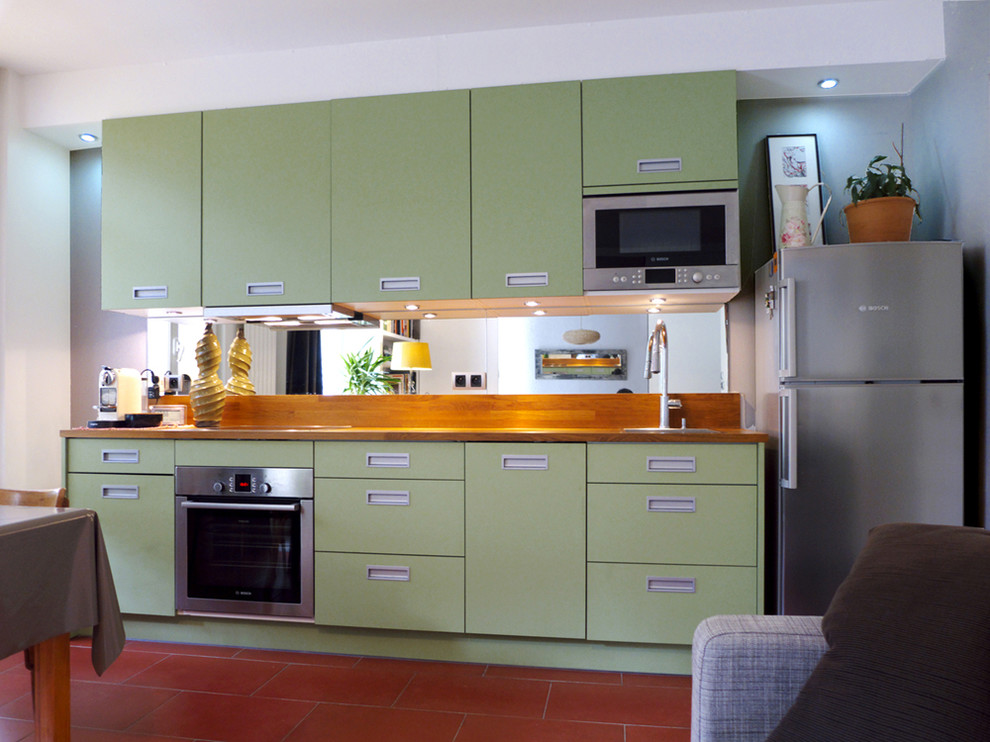 Foto di una cucina contemporanea di medie dimensioni con top in legno, paraspruzzi a specchio, elettrodomestici da incasso, pavimento in terracotta e pavimento rosso