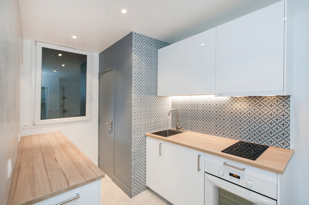 This is an example of a medium sized contemporary galley enclosed kitchen in Paris with wood worktops, grey splashback, light hardwood flooring and beige worktops.