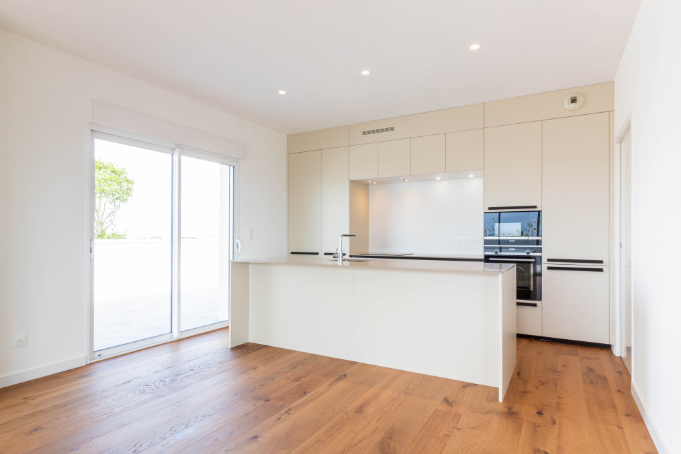 Design ideas for a medium sized contemporary galley open plan kitchen in Nantes with beaded cabinets, beige cabinets, granite worktops, black appliances, an island and beige worktops.