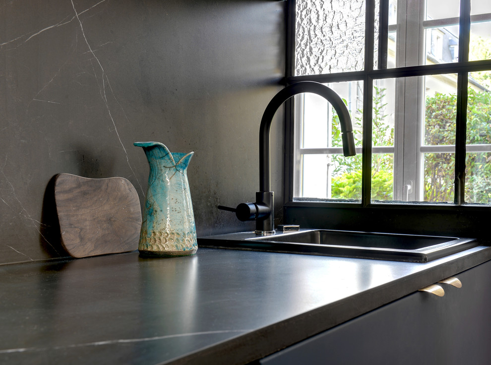 Klassisk inredning av ett litet kök, med en nedsänkt diskho, luckor med profilerade fronter, blå skåp, kaklad bänkskiva, svart stänkskydd, stänkskydd i keramik, svarta vitvaror, cementgolv och blått golv