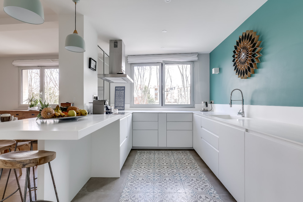 Moderne Küche in U-Form mit integriertem Waschbecken, flächenbündigen Schrankfronten, weißen Schränken, Halbinsel, grauem Boden und weißer Arbeitsplatte in Paris