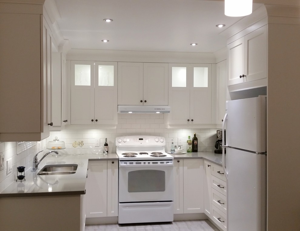 Medium sized traditional u-shaped kitchen in Montreal with a double-bowl sink, shaker cabinets, white cabinets, quartz worktops, white appliances, porcelain flooring and no island.