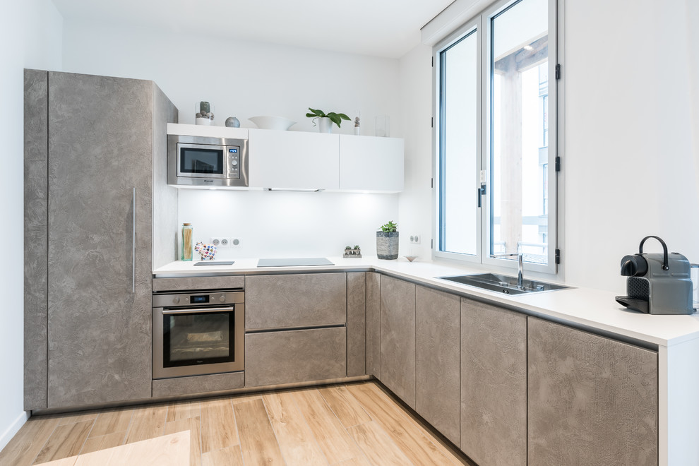 Immagine di una cucina contemporanea di medie dimensioni con ante grigie, top in laminato, paraspruzzi bianco, pavimento in laminato e nessuna isola