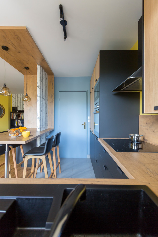 Mittelgroße Moderne Wohnküche in L-Form mit Arbeitsplatte aus Holz, Rückwand aus Holz, Küchengeräten aus Edelstahl, Kücheninsel und grauem Boden in Paris