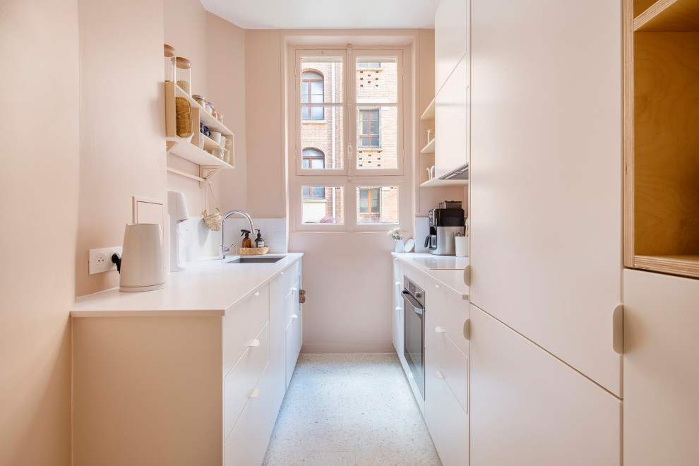 This is an example of a small contemporary galley enclosed kitchen in Paris with a submerged sink, beaded cabinets, pink cabinets, quartz worktops, white splashback, terracotta splashback, integrated appliances, terrazzo flooring, no island, white floors and pink worktops.