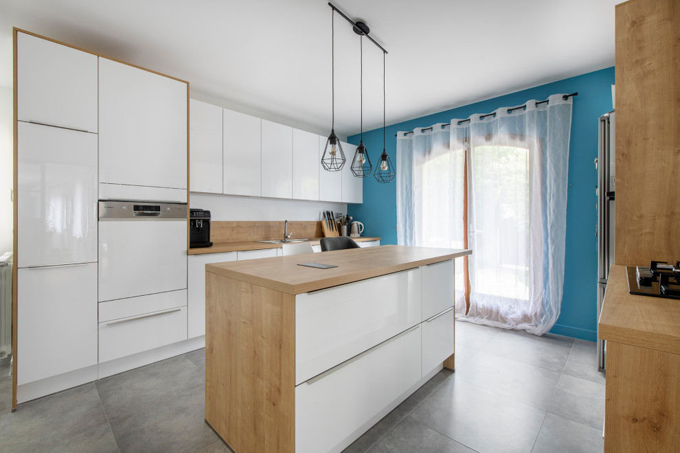 Huge trendy galley ceramic tile and gray floor kitchen photo in Paris with a drop-in sink, flat-panel cabinets, white cabinets, wood countertops, beige backsplash, wood backsplash, paneled appliances, an island and beige countertops