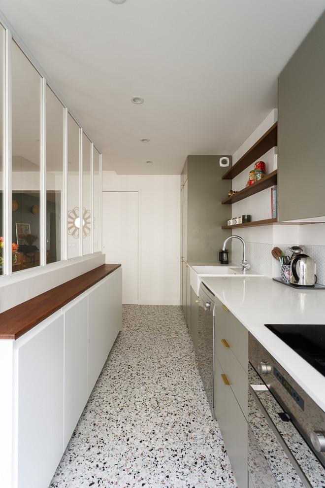 Design ideas for a medium sized modern single-wall open plan kitchen in Paris with a submerged sink, flat-panel cabinets, green cabinets, white splashback, cement tile splashback, stainless steel appliances, terrazzo flooring, an island, multi-coloured floors and white worktops.
