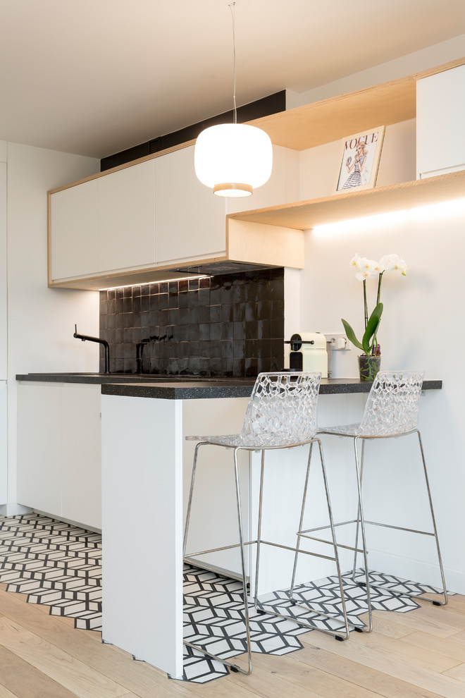 Inspiration för ett litet skandinaviskt linjärt kök med öppen planlösning, med en undermonterad diskho, vita skåp, laminatbänkskiva, svart stänkskydd, stänkskydd i terrakottakakel, integrerade vitvaror, cementgolv, vitt golv och släta luckor