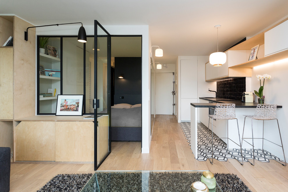 Small scandi single-wall open plan kitchen in Paris with a submerged sink, white cabinets, laminate countertops, black splashback, terracotta splashback, integrated appliances, cement flooring, no island, white floors and flat-panel cabinets.