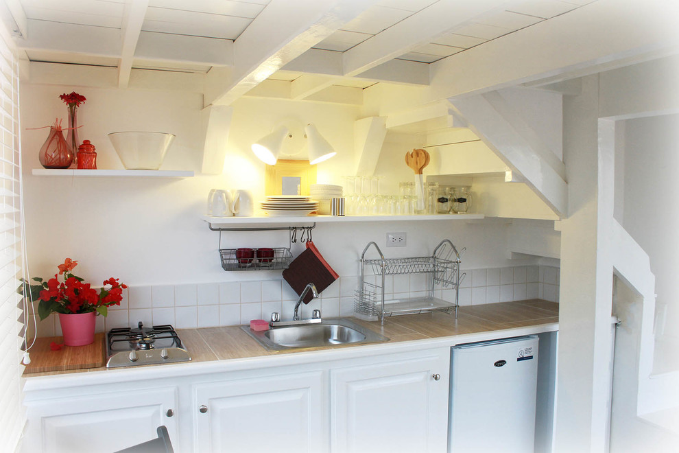 他の地域にある低価格の小さな北欧スタイルのおしゃれなダイニングキッチン (一体型シンク、タイルカウンター、白いキッチンパネル、セラミックタイルのキッチンパネル、白い調理設備、セラミックタイルの床) の写真