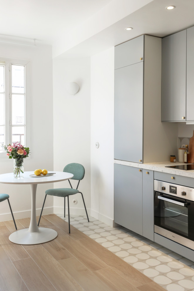 Skandinavische Wohnküche ohne Insel mit flächenbündigen Schrankfronten, grauen Schränken, beigem Boden und weißer Arbeitsplatte in Paris