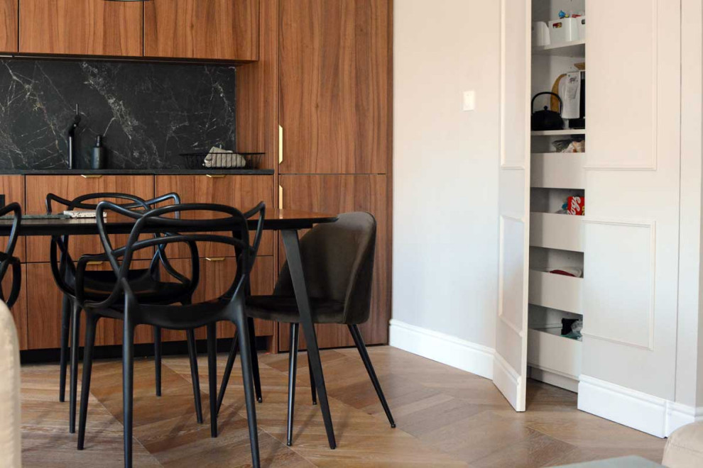 Idée de décoration pour une cuisine ouverte linéaire minimaliste en bois brun de taille moyenne avec un évier 1 bac, un plan de travail en stratifié, une crédence noire, un électroménager noir, un sol en bois brun, un sol marron et plan de travail noir.