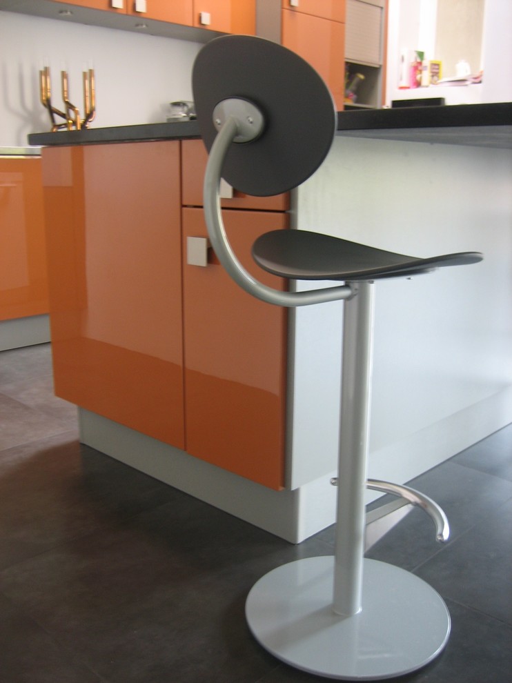 Bild på ett mellanstort funkis grå grått kök, med en undermonterad diskho, luckor med profilerade fronter, orange skåp, integrerade vitvaror, en köksö, grått golv och klinkergolv i keramik