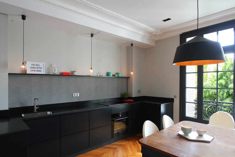 Стильный дизайн: угловая кухня среднего размера в современном стиле с обеденным столом, черными фасадами и серым фартуком без острова - последний тренд