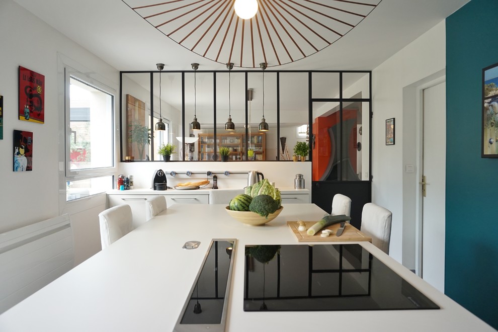 Photo of a large contemporary l-shaped enclosed kitchen in Paris with a submerged sink, an island, white cabinets and black appliances.