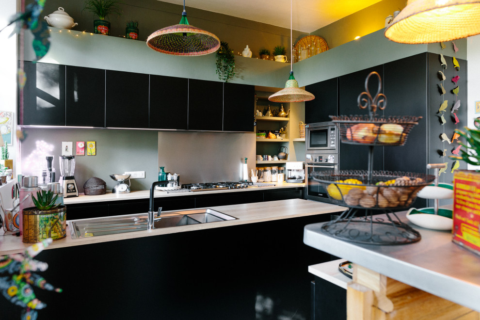 Eklektisk inredning av ett mellanstort kök, med en dubbel diskho, svarta skåp, laminatbänkskiva, grått stänkskydd, integrerade vitvaror och en köksö