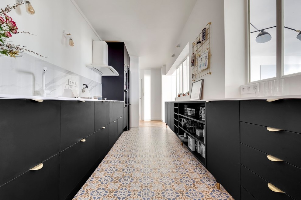 パリにあるお手頃価格の広いコンテンポラリースタイルのおしゃれなキッチン (白いキッチンカウンター、一体型シンク、フラットパネル扉のキャビネット、黒いキャビネット、ラミネートカウンター、白いキッチンパネル、大理石のキッチンパネル、黒い調理設備、セメントタイルの床、ベージュの床) の写真
